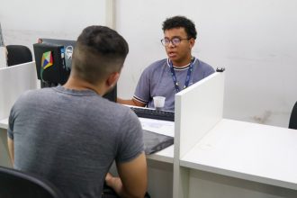 Dois homens em um escritório do Sine em Manaus, um atendendo e outro sendo atendido.