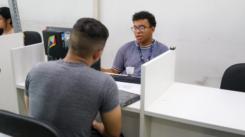 Dois homens em um escritório do Sine em Manaus, um atendendo e outro sendo atendido.