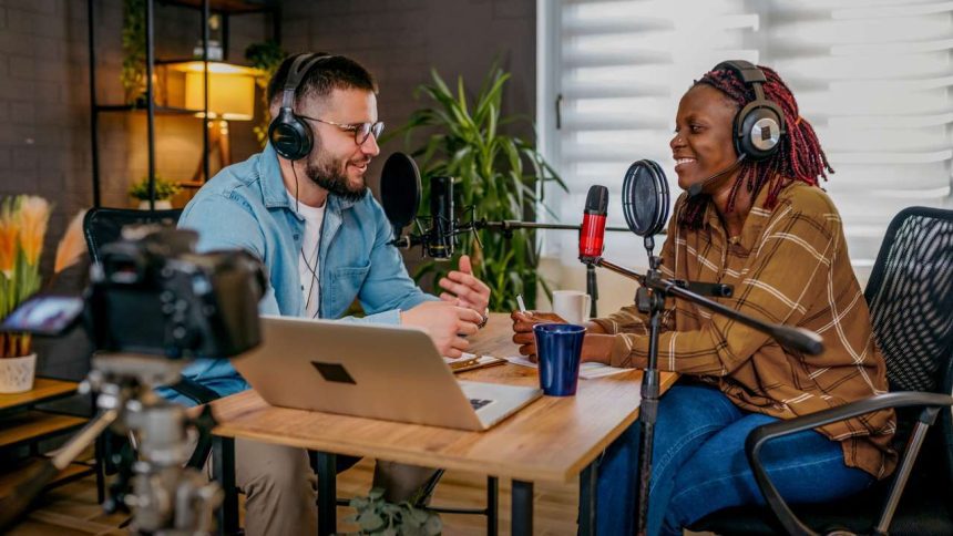 Dois podcasters gravando um episódio em estúdio com microfones e fones de ouvido.