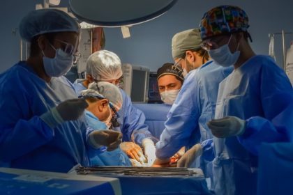 Equipe médica realiza cirurgia em centro cirúrgico com luzes intensas.