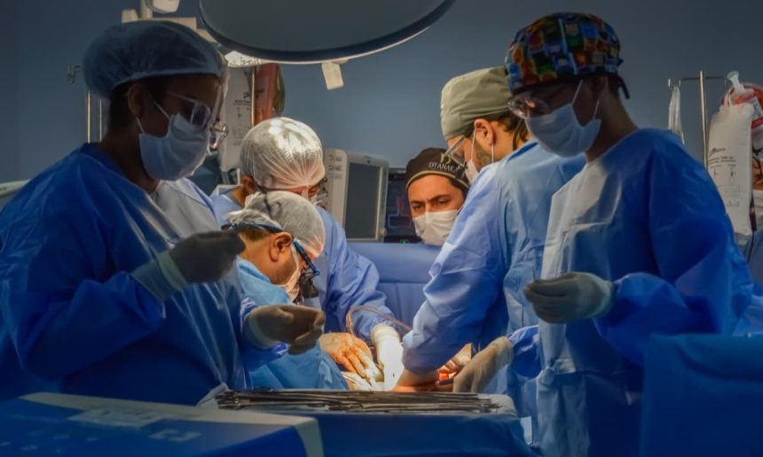 Equipe médica realiza cirurgia em centro cirúrgico com luzes intensas.