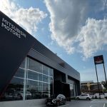 Fachada da concessionária Mitsubishi Motors em Manaus, com céu azul e nuvens.