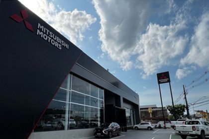 Fachada da concessionária Mitsubishi Motors em Manaus, com céu azul e nuvens.