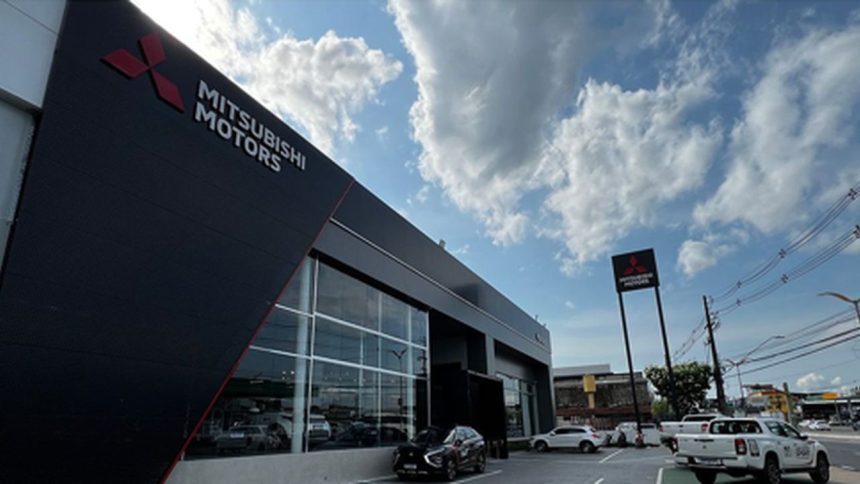 Fachada da concessionária Mitsubishi Motors em Manaus, com céu azul e nuvens.
