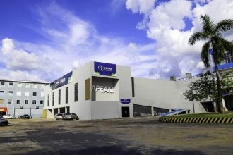 Fachada da FAPEAM, instituição de pesquisa do Amazonas, sob céu azul com nuvens.