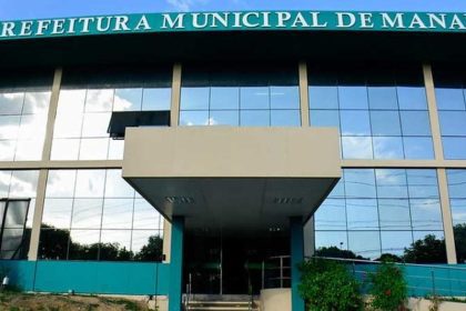 Fachada da Prefeitura Municipal de Manaus, com céu azul refletido nos vidros.