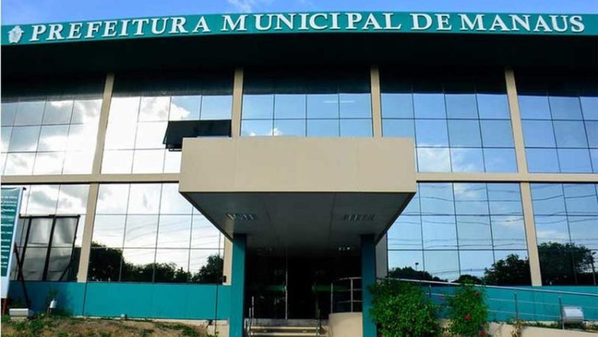 Fachada da Prefeitura Municipal de Manaus, com céu azul refletido nos vidros.