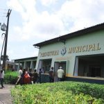 Fachada da Prefeitura Municipal de Nova Olinda do Norte, com pessoas entrando e saindo.