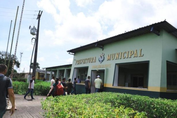 Fachada da Prefeitura Municipal de Nova Olinda do Norte, com pessoas entrando e saindo.