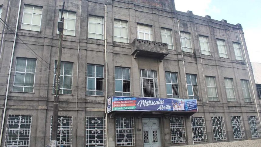 Fachada de escola cinza com letreiro de matrículas abertas.