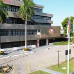 Fachada do Ministério Público, com prédios e palmeiras.