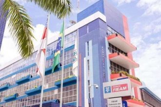 Fachada do prédio da FIEMG com bandeiras do Brasil e de estados, com palmeiras e céu azul ao fundo.