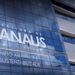 Fachada do prédio da Prefeitura de Manaus, com os dizeres 'Meio Ambiente e Sustentabilidade'.