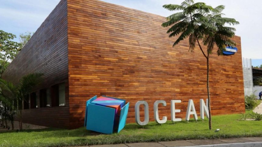 Fachada do Samsung Ocean com design moderno em madeira, com logo da Samsung e escultura.