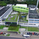 Fachada moderna da Faculdade Matias Machline com área verde e estacionamento.