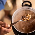 Feijão-fradinho sendo cozido em panela, com fumaça e colher