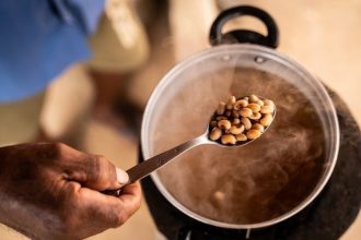 Feijão-fradinho sendo cozido em panela, com fumaça e colher