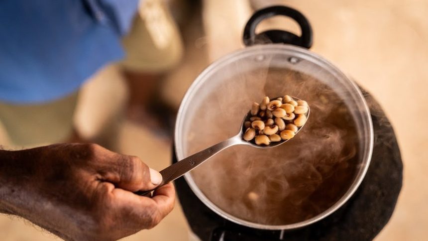 Feijão-fradinho sendo cozido em panela, com fumaça e colher