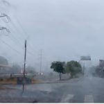 Foto de rua em dia chuvoso com postes de energia e semáforo