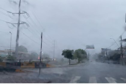 Foto de rua em dia chuvoso com postes de energia e semáforo