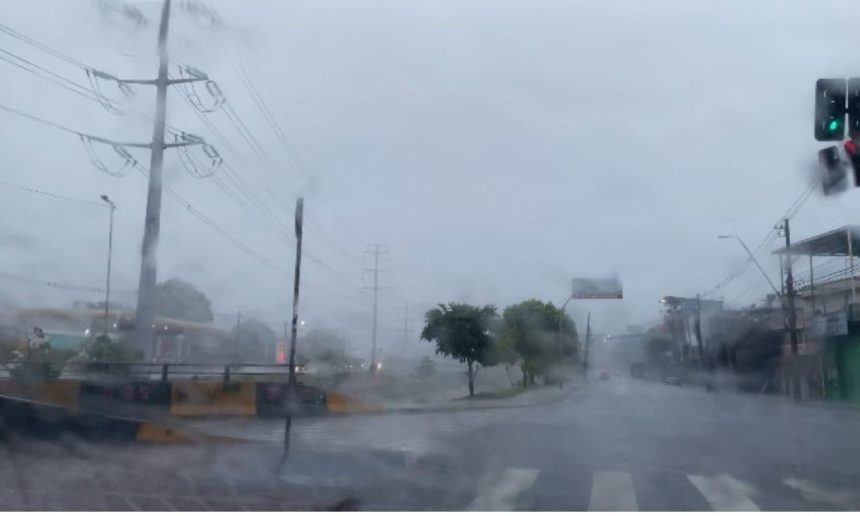Foto de rua em dia chuvoso com postes de energia e semáforo