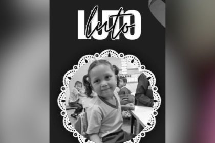 Foto em preto e branco de menina sorrindo com a palavra Luto no topo, em homenagem.