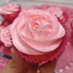 Cupcakes decorados com glacê rosa em formato de rosa e glitter.