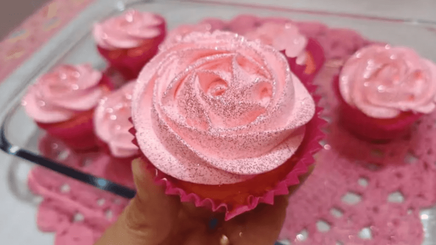 Cupcakes decorados com glacê rosa em formato de rosa e glitter.