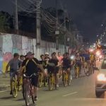 Grupo de ciclistas pedalam à noite em uma avenida movimentada em Manaus.