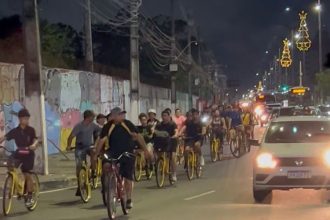 Grupo de ciclistas pedalam à noite em uma avenida movimentada em Manaus.