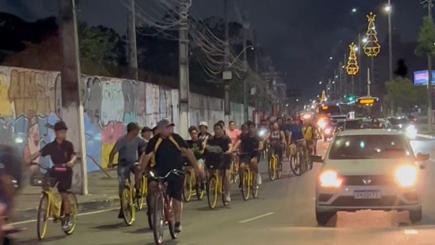 Grupo de ciclistas pedalam à noite em uma avenida movimentada em Manaus.