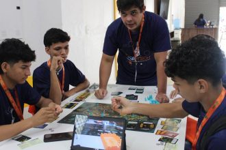 Grupo de jovens jogando jogo de tabuleiro durante o torneio Jogatech em Tefé, Amazonas.