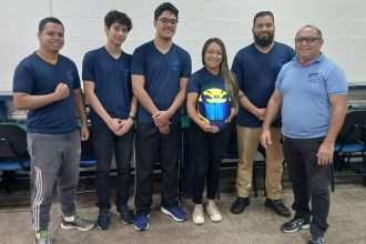 Grupo de estudantes vestindo uniformes da Fucapi, segurando um capacete, em ambiente interno.