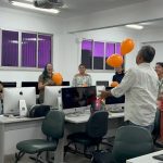 Grupo em oficina sobre cinema, educação e direitos humanos, com balões laranja em um ambiente de computadores.