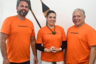 Grupo posa sorrindo, vestindo camisetas laranja com logo da Tropos Amazônia.