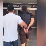 Homem algemado sendo conduzido por policial após prisão em Manaus.