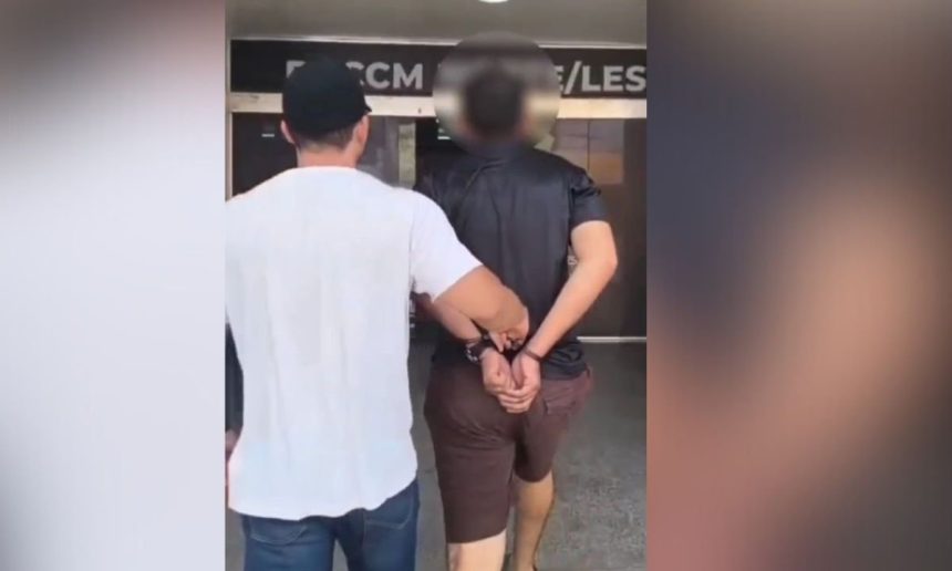 Homem algemado sendo conduzido por policial após prisão em Manaus.