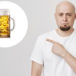 Homem careca aponta para um copo de cerveja em um círculo branco.