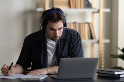 Homem com fones de ouvido estudando online em frente ao laptop