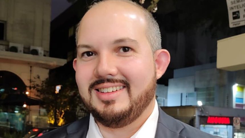 Homem sorrindo com barba, possivelmente em evento de inovação