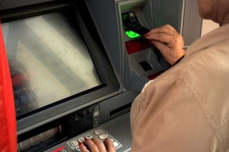 Idoso usando caixa eletrônico para sacar dinheiro.