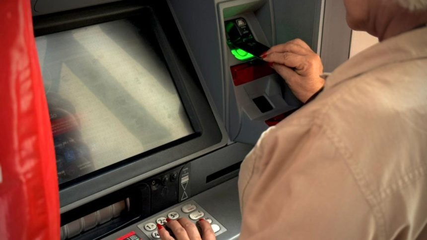 Idoso usando caixa eletrônico para sacar dinheiro.