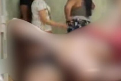 Imagem borrada de cena possivelmente de invasão e ferimento, com pessoas ao fundo.