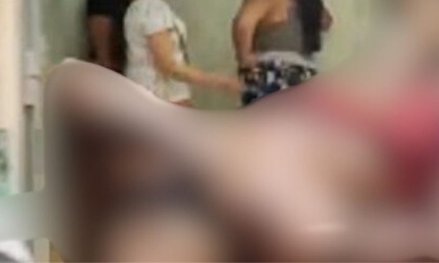 Imagem borrada de cena possivelmente de invasão e ferimento, com pessoas ao fundo.