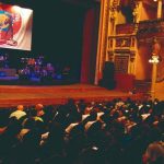 Interior de teatro com palco e plateia lotada durante o Festival Amazonas de Música.