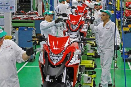 Linha de produção na fábrica da Honda em Manaus, com motos em montagem e trabalhadores uniformizados