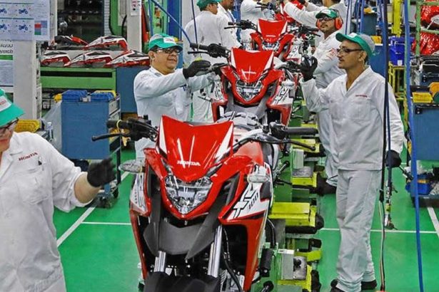 Linha de produção na fábrica da Honda em Manaus, com motos em montagem e trabalhadores uniformizados