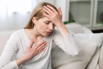 Mulher com a mão na testa e no peito, demonstrando ansiedade.