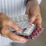 Mãos segurando cartelas de comprimidos