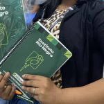 Mulher segura cadernos do Instituto Rio Negro com logotipos, em um evento.